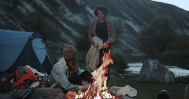 Japão senhora com seu namorado passar noite romântica juntos no acampamento ao lado de fogueira, cara traz um cobertor para sua namorada e feliz abraçando uns aos outros . — Vídeo de Stock