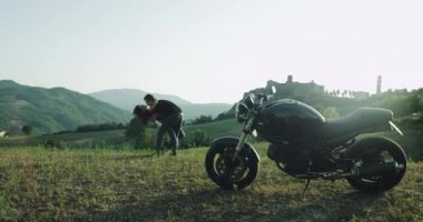 Güzel çift bir romantik birlikte doğa ortasında muhteşem yerde vakit onlar, onları ayakta sarılma bir siyah motosiklet