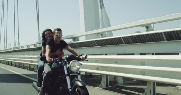 彼らは一緒に時間を楽しむ高速道路の日当たりの良い夏の日にオートバイに乗ってがあるカメラの美しいカップルの前にビデオをキャプチャします。 — ストック動画