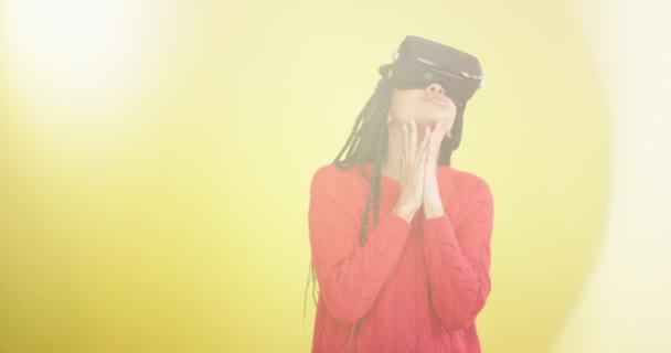 Захоплена африканська леді з довгими дредлоками, використовуючи окуляри віртуальної реальності, щоб досліджувати світ в студії з жовтим тлом . — стокове відео