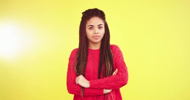 Retrato en un estudio con un fondo amarillo de una mujer africana que se ve triste delante de la cámara con las manos cruzadas y con un suéter rojo — Vídeos de Stock