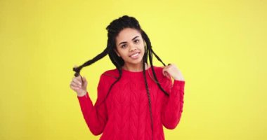 Sarı arka plan duvar Afrikalı kadın onu uzun saçlı dreadlocks ile oynama ve büyük gülümseyen kamera önünde kırmızı bir kazak giyen arıyorum güzel.
