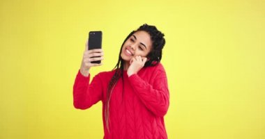 Şaşırtıcı Afrikalı kadın almak onun smartphone içinde sarı arka plan duvar stüdyo ile güzel bir selfie.