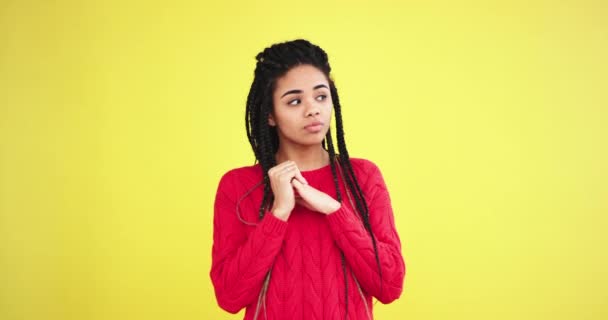 Fechar jovem bonita senhora étnica africana olhando diretamente para a câmera e curiosamente acho que as decisões a tomar por si mesma, ela gesticulando com as mãos no estúdio com um fundo amarelo — Vídeo de Stock