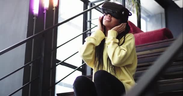 Charismatická dáma těší čas s virtuální realita brýle v moderní budově úřadu sedí na schodech — Stock video