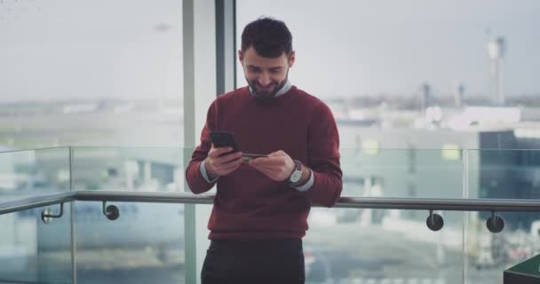 Gelukkig kantoorbediende in een modern gebouw controleren zijn bankrekening online creditcard zijn smartphone en bank, eind hij zijn blij en opgewonden. 4k. Slow-motions — Stockvideo