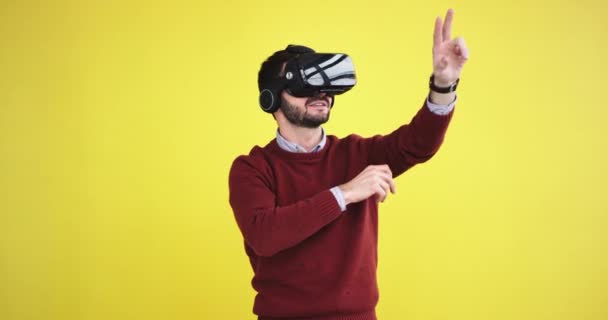 Beau gars utilisant un VR heureux il toucher virtuel le programme pour sélectionner ce qu'il veut, il est très excité dans le studio avec un mur d'arrière-plan jaune . — Video