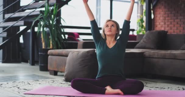 Sabah sarışın kadın Yoga meditasyon var sağlıklı bir yaşam tarzı, o vücut germe ve onun modern apartman çatı katı büyük pencere manzaralı bir egzersiz başlatmak hazırlanıyor — Stok video