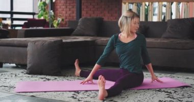 Bir modern loft çekici sarışın Bayan rahat bir spor ile sağlıklı yaşam için sabah vücut germe için yoga egzersizleri pratik