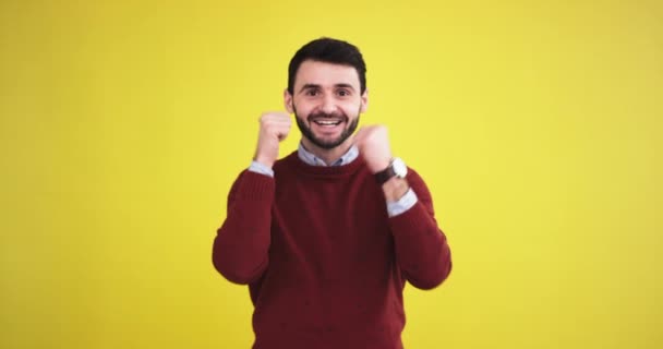 Gelukkig charismatische jonge man in de studio met een gele achtergrond muur op zoek direct naar de camera glimlachen groot en tonen een grote achtige — Stockvideo