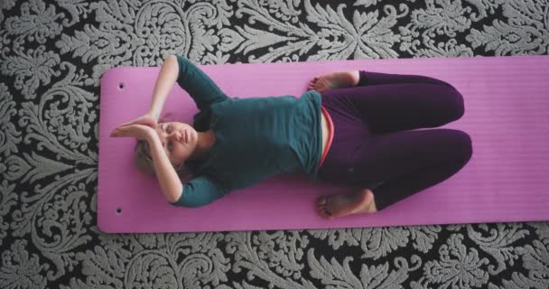 Senhora carismática tem uma meditação na parte da manhã ela faz uma poses de ioga para obter mais energia para todo o dia em casa no chão no tapete rosa — Vídeo de Stock
