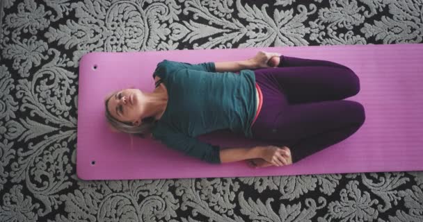 Леди растяжения тела делает упражнения йоги утром дома она сидит в розовый мат, здоровый образ жизни — стоковое видео