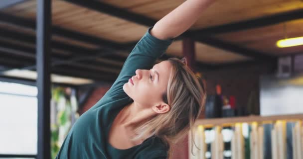 Retrato de uma senhora europeia com cabelo loiro praticando exercícios de ioga pela manhã em casa em uma sala de estar moderna em seu tapete ela faz diferentes poses de ioga. movimentos lentos — Vídeo de Stock