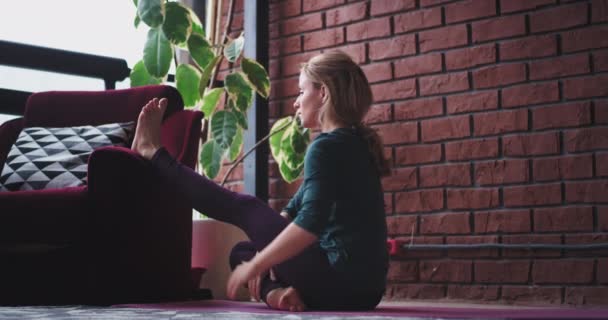 Lady at home practicing yoga in her relaxing space she stretching legs and body to get more energy for all day , modern and sophisticated design interior — Stock Video