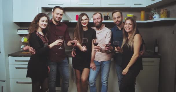 Велика компанія молодих хлопців і леді влаштовують домашню винну вечірку, яку вони дивляться прямо на камеру, посміхаючись багато і підбадьорює келихами для вина. 4k — стокове відео