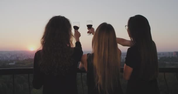 Horário de pôr do sol três senhoras na varanda no topo do edifício admirar o pôr do sol todos juntos e beber um copo de vinho . — Vídeo de Stock