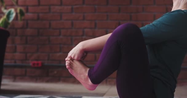 Γυναίκα με ένα τέλειο σώμα τέντωμα των ποδιών και εξάσκηση γιόγκα ασκήσεις στο σπίτι το πρωί, φορώντας ένα άνετο αθλητικά είδη — Αρχείο Βίντεο