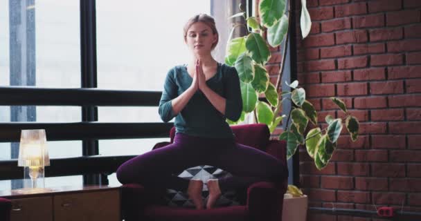 Op een rode sofa dame het beoefenen van de yoga-oefeningen ze evenwicht van het lichaam op de handen, en krijg meer geconcentreerd op de oefeningen thuis in de ochtend. — Stockvideo