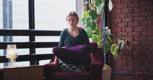 Charismatic lady make a balance exercises she practicing yoga in the morning at home on the sofa , wearing a comfortable sportswear. — Stock Video