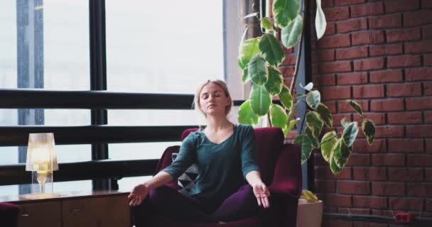 In een moderne en urban design plaats thuis lady praktizerende yoga meditatie houdingen in de ochtend op rode sofa ze de ogen dicht en geconcentreerd om meer energie voor de hele dag. 4k — Stockvideo