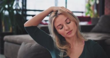 İyi sabah vücut germe genç bayan closeup görünüyor o evde oturma odası modern tasarımı, rahat bir spor giyim giymek pratik yoga. 4k