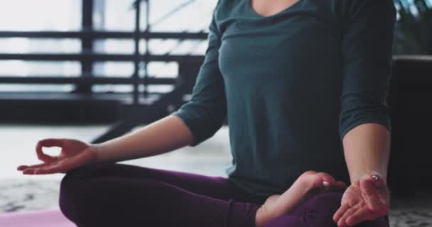 Détails de la méditation de yoga à la maison femme pratiquant pour elle-même, dans un appartement penthouse moderne, elle s'assied sur le tapis de yoga . — Video