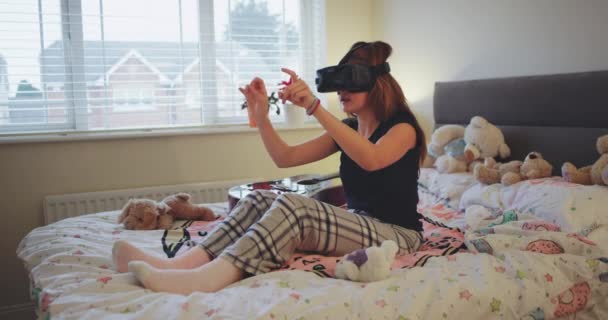 Joven adolescente en la cama con ropa de casa, jugando con las gafas de realidad virtual, tocando virtual con el dedo para seleccionar un programa . — Vídeo de stock