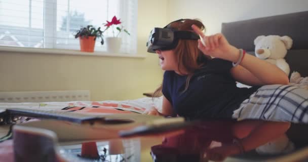 Sorrindo e muito entusiasmada adolescente vestindo um pijama em seu quarto, ela usa óculos de realidade virtual para explorar o mundo. 4k — Vídeo de Stock