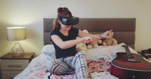 In de tiener slaapkamer jonge dame speelt met een virtual reality bril op het bed zeer enthousiast en charismatische. — Stockvideo