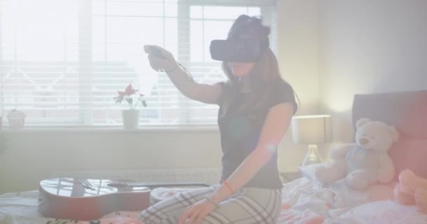 In una stanza soleggiata e accogliente una ragazza adolescente che gioca con un occhiali di realtà virtuale molto concentrata lei esplorare un mondo di gioco virtuale. 4k — Video Stock