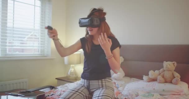Милая харизматичная молодая девушка-подросток, играющая в очках виртуальной реальности в своей спальне, очень весело проводит время, наслаждаясь игрой. 4k — стоковое видео