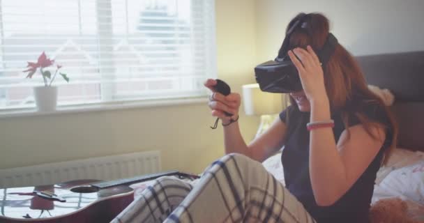 Retrato de una joven adolescente en un pijama jugando con una VR que están muy impresionados sobre el juego y explorar el mundo juego . — Vídeo de stock