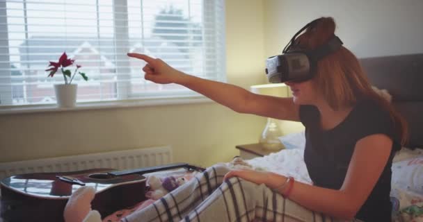 Χαρούμενος και ενθουσιώδης κορίτσι παίζει με ένα γυαλιά εικονικής πραγματικότητας στο υπνοδωμάτιό της, φορώντας μια πιτζάμες. — Αρχείο Βίντεο