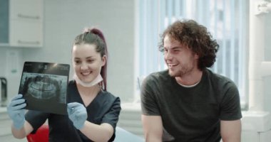 Oldukça genç adam var onun diş hekimi doktor ziyareti diş röntgen açıklamak ve dikkatli bir şekilde onun diş sorunu gösteren. 4k