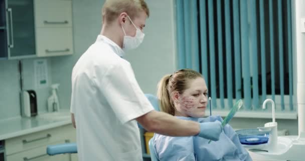 Новое изобретение для кожи омоложения prp или вампирской процедуры для лица врач дает своему пациенту зеркало, чтобы посмотреть на ее лицо после процедуры микро-иглы, пациент смотрит в зеркало — стоковое видео
