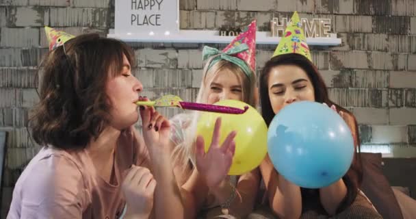 Portret trzech charyzmatyczny Panie przed kamerą obchodzi urodziny party w domu przy użyciu strony dekoracje do zabawy czas, przed kamerą, dmuchanie balonów. 4k — Wideo stockowe
