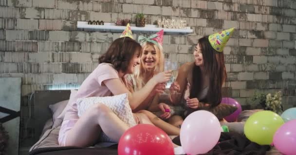 Señoritas guapas celebrando en casa en el dormitorio el cumpleaños de alguien s, muy felices bebiendo champán y sonriendo globos grandes y decoraciones de cumpleaños alrededor. mociones lentas — Vídeos de Stock