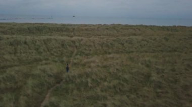 Bir dron havadan video alarak plaja yürüme çanta bir turist yeşil alan ile seyahat.