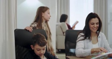 Üç çocuk oturma odasında ödev yapıyor ile büyük Olgun Anne gülümseyen, çok onlar meşgul, gözlük ile arka plan anneanne bir kitap okuma konsantre