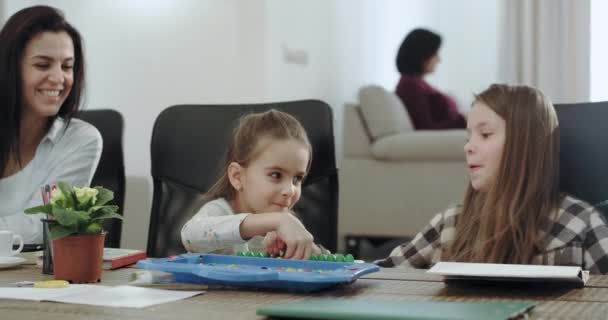 Crianças muito carismáticas duas meninas e um menino se divertem com sua mãe madura na mesa eles pintam juntos e passam um ótimo tempo. 4k — Vídeo de Stock