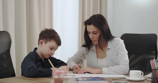 良い探している成熟した母は彼女の息子と時間を過ごし、彼らは近代的な家のデザインで生活に一緒に絵を描く — ストック動画