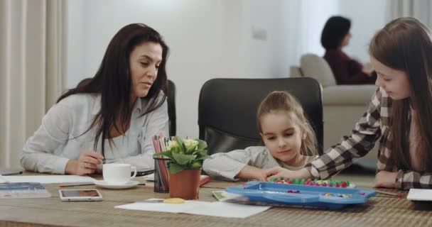 Mycket karismatisk och mogen mamma har en fantastisk tid med sina barn i ett modernt vardags rum målning och har ett hantverk tid — Stockvideo