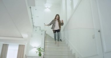 Sabah sevimli kardeş ve kız kardeşi, onların küçük kız kardeşi ve olgun anne birbirlerine mutlu ve büyük gülümseyen sarılma modern bir evde merdivenlerden aşağı gidin. 4k