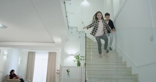 Charismatische kleine jongen en meisje in de ochtend loopt naar de eerste verdieping naar een grote woonkamer gaan ze naar hun moeder en zus om te zeggen goedemorgen en knuffelen mooie elkaar — Stockvideo