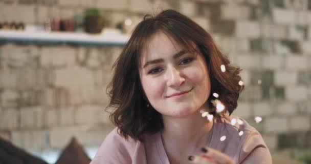 Retrato de una dama con moteado usando fuegos artificiales brillantes delante de la cámara sonriendo y disfrutando del tiempo con ella misma — Vídeos de Stock