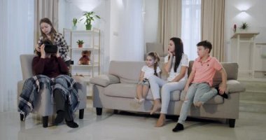 Onun torunları ve olgun bir anne ile Büyükanne yeni bir sanal gerçeklik gözlüğü yeğeni keşfetmek kanepede birlikte bir zaman geçirmek onu büyükanne Vr koymak.