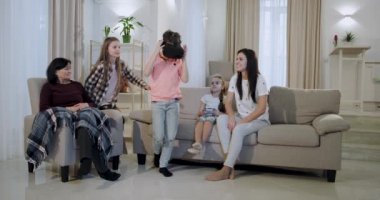 Olgun anne üç çocuğu ve bir büyükanne oturma odasında kanepede oturan ve sanal gerçeklik gözlük ile oynarken onlar çok bu yeni teknoloji hakkında etkilendim