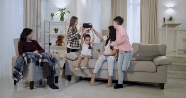 Anneleri ve büyükanne ile üç çocuk birlikte sanal gerçeklik gözlük ve psp onlar çok etkilendim ve coşkulu oynarken eğlenceli bir zaman var