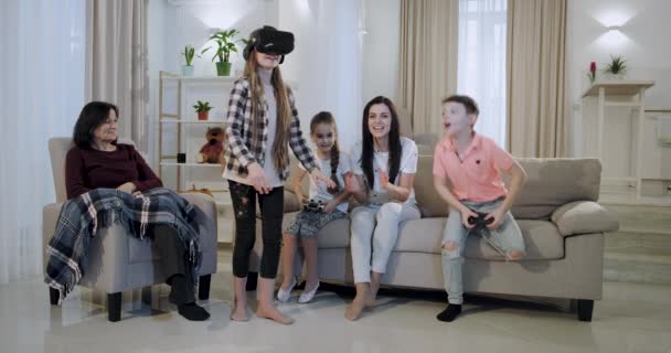 Веселые семейные дети, играющие в очки виртуальной реальности вместе с мамой и бабушкой в просторной гостиной, очень счастливы и впечатлены . — стоковое видео