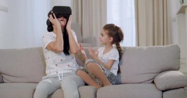 Karizmatik olgun anne kızı ile kanepede otururken , dünya kadın keşfetmek için sanal gerçeklik gözlüğü kullanarak çok etkilendim ve hevesli